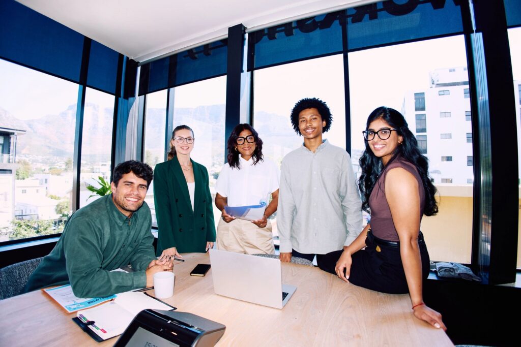 Wide shot of cheerful business team standing together around meeting table in modern office